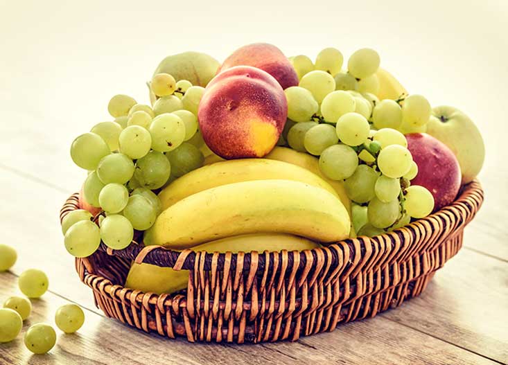Fruit basket with bananas, grapes and peaches
